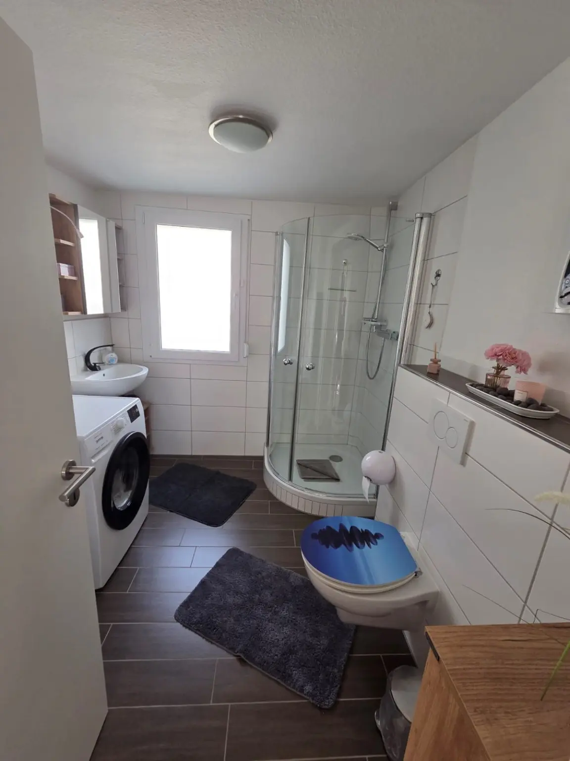 Badezimmer mit Dusche, Waschmaschine, Fön und Schminkspiegel