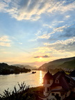 Auf der rechten Seite des Bildes fällt der einzigartige Baustil des Gebäudes ins Auge, während im Hintergrund die untergehende Sonne sich in der Mosel spiegelt.